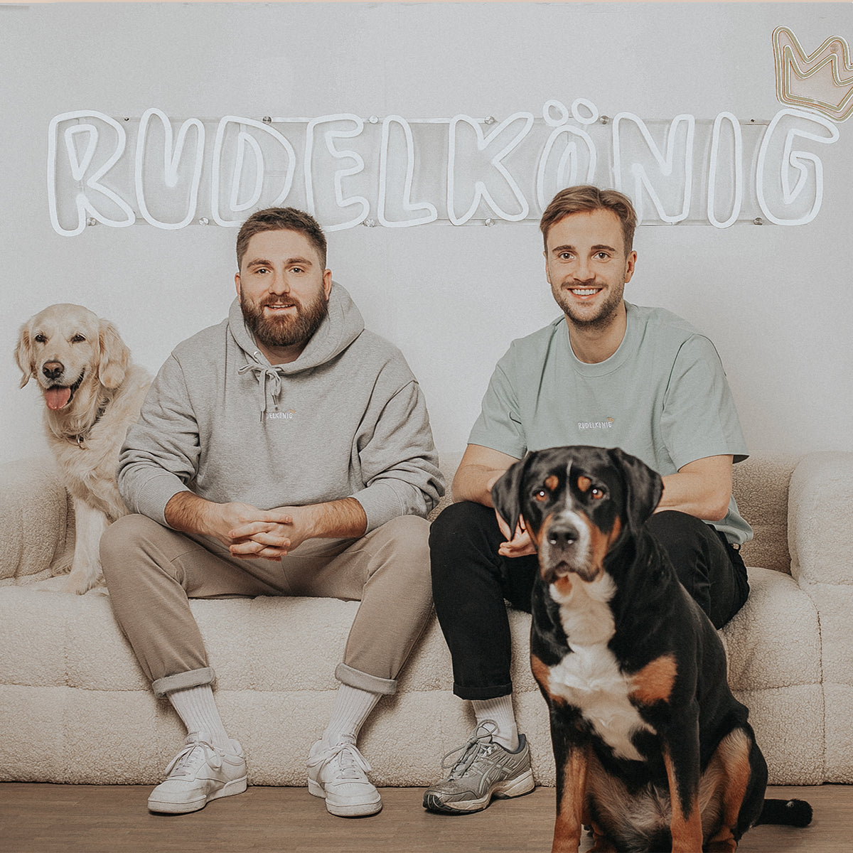 Die beiden Rudelkönig Gründer Marc und Felix auf einer Couch mit ihren beiden Hunden
