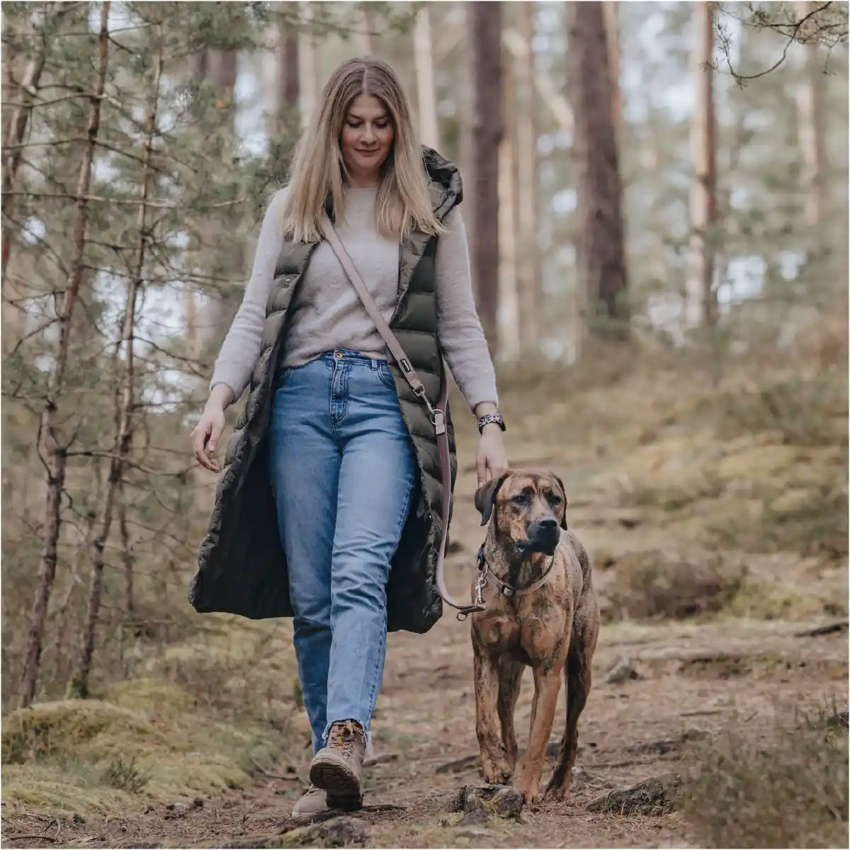 Frauchen geht mit ihrem Hund und der Rudelkönig Umhängeleine Paola im Wald spazieren.