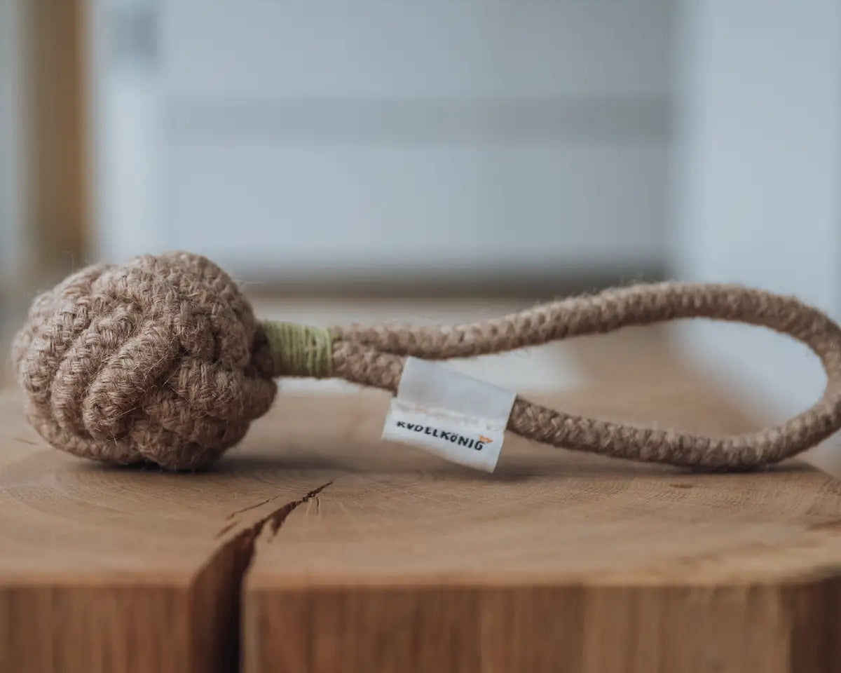 Rudelkönig Seilspielzeug aus 100% Baumwolle liegt auf einem Baumstumpf im Wohnzimmer.
