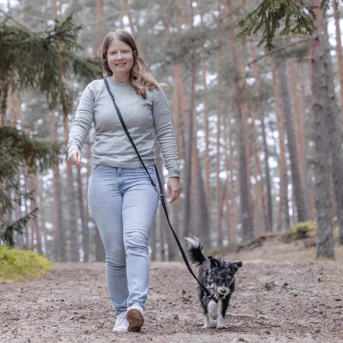 Frauchen geht mit ihrem Hund und der Rudelkönig Hundeleine Bella in schwarz im Wald Gassi. Die Leine ist locker umgehängt.