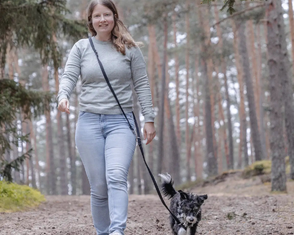Frauchen geht mit ihrem Hund und der Rudelkönig Hundeleine Bella in schwarz im Wald Gassi. Die Leine ist locker umgehängt.