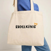Frau trägt den Rudelkönig Baumwollbeutel in beige mit Logo Print über der Schulter im Studio.